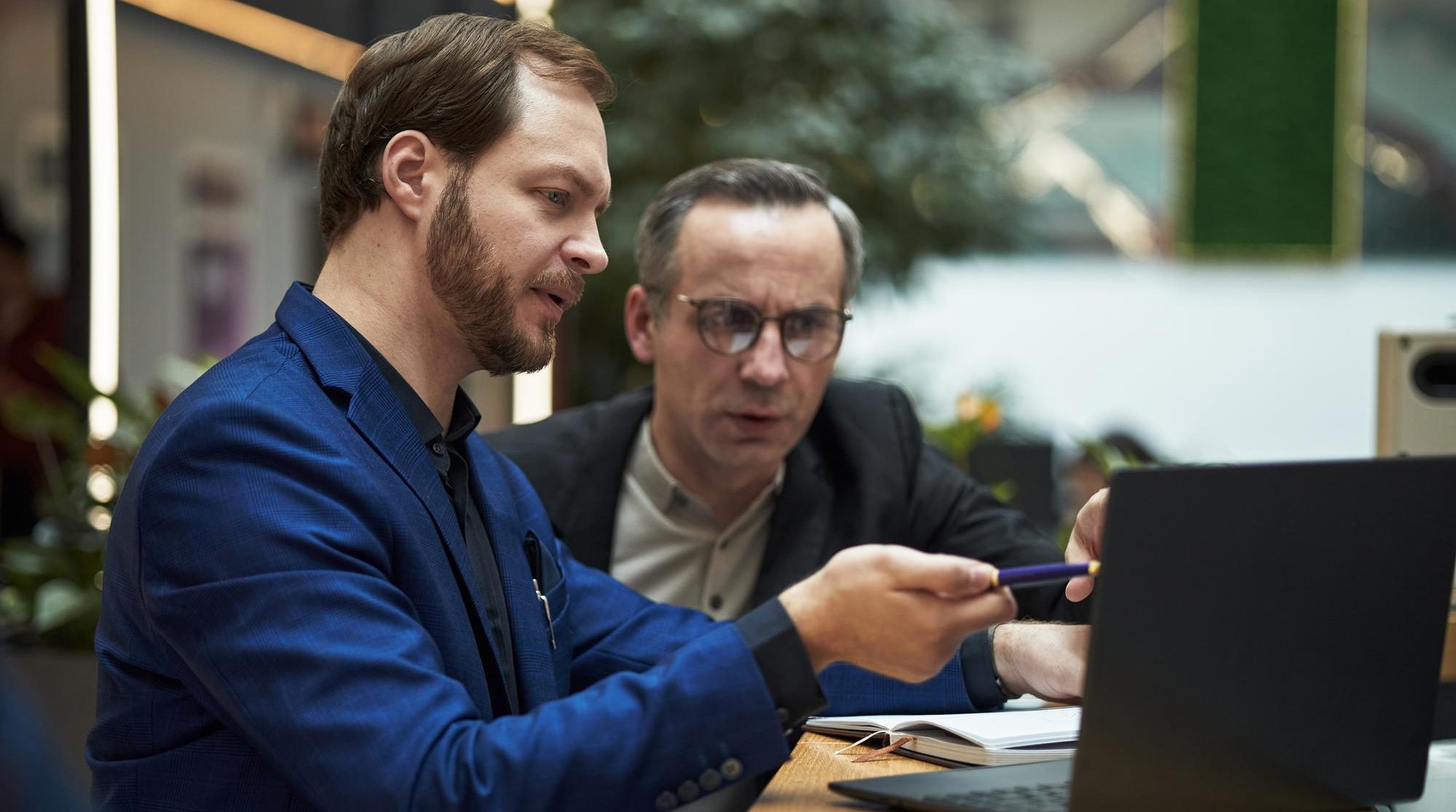 Zwei M&auml;nner besprechen sich am Laptop in einem hellen B&uuml;ro