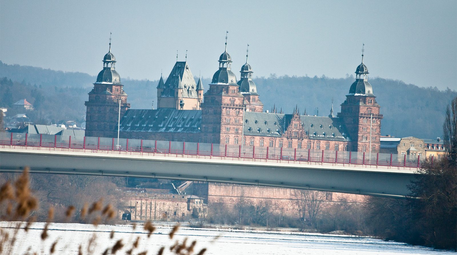 Schloss Johannisburg im Winter, vom Main aus gesehen, davor die Brücke und verschneites Schilfufer