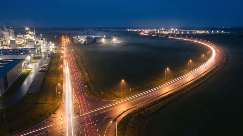 Straßengabelung bei Nacht aus der Luft mit Lichtspuren